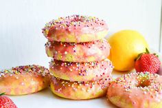 a stack of doughnuts with sprinkles next to lemons and strawberries