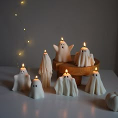 some white candles are sitting on a table with ghost figures and lights in the background