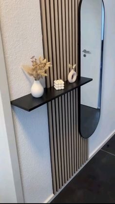 a black shelf with two white vases on it and a mirror in the corner