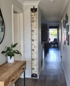 a wooden table sitting next to a tall growth chart on a wall in a living room