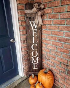 two pumpkins are sitting on the front porch next to a welcome sign that says welcome