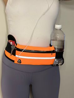 an orange waist belt attached to a woman's body with water bottle in it