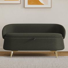 a green couch sitting on top of a wooden floor next to two pictures above it