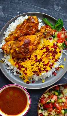 a plate with rice, meat and vegetables on it next to two bowls of sauce