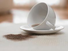 a white coffee cup sitting on top of a saucer filled with brown liquid next to a spoon