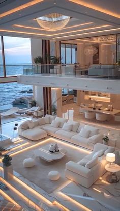 a living room filled with lots of white furniture next to the ocean in front of a large window