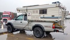 a truck with a camper attached to it's bed parked in the rain