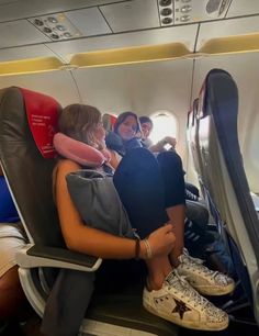 three people sitting on an airplane seat with their feet propped against each other's back