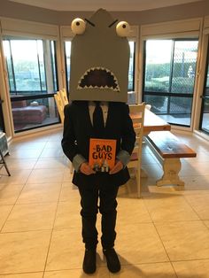 a boy in a suit and tie holding a book with a monster head on it