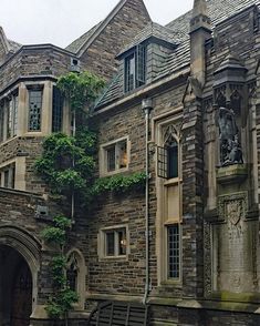 an old stone building with ivy growing on it's side and benches in front