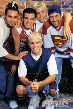 a group of young men standing next to each other in front of a brick wall