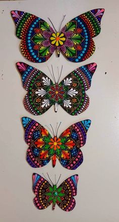 three colorful butterflies on a white surface