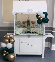 a buffet table with balloons and confetti on the top, along with green and white decorations