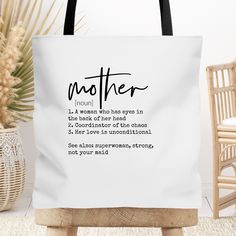 a white tote bag sitting on top of a wooden chair next to a potted plant