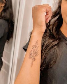 a woman with a flower tattoo on her arm is standing in front of a mirror