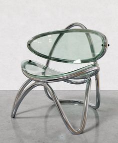 a glass and metal chair sitting on top of a cement floor