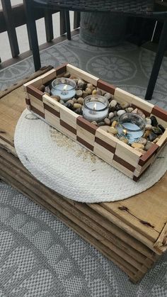 two tea lights are placed in a wooden box on top of some wood planks