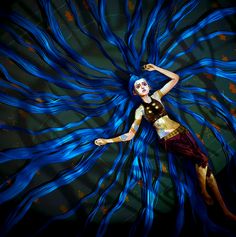 a woman with blue hair is dancing in the air