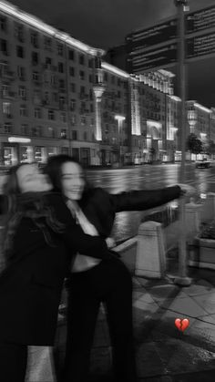 black and white photograph of two people hugging in front of a body of water at night