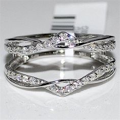 two white gold wedding rings with diamonds on top of each other and one diamond in the middle