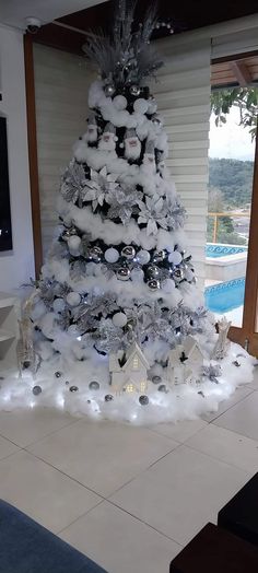 a white christmas tree is decorated with silver ornaments