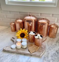 a kitchen counter topped with copper colored pots and pans filled with marshmallows