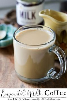 a glass mug filled with coffee sitting on top of a wooden table next to other cups