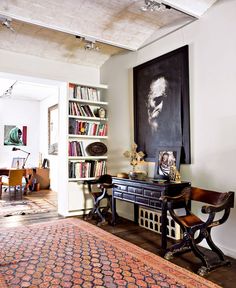 a living room filled with furniture and bookshelves next to a painting on the wall