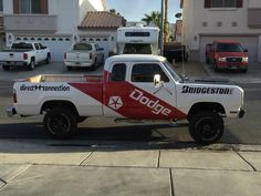 a white and red dodge truck parked in front of a house