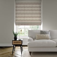 a living room scene with focus on the couch and window blinds that have an intricate pattern