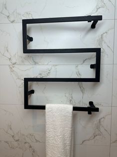 two black towel racks in a bathroom with marble walls and white tiles on the wall