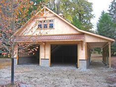 a wooden garage sitting in the middle of a field next to a tree with leaves on it