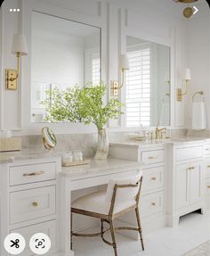 a white bathroom with marble counter tops and gold accents