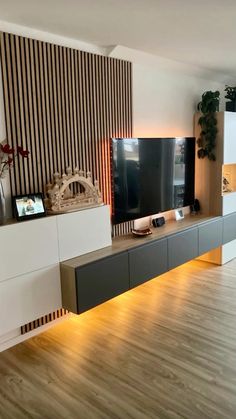 a living room with a large television on the wall next to a wooden floor and white cabinets