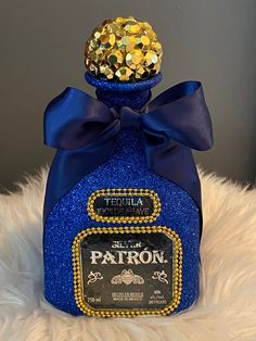 a blue bottle with a gold cap on top sitting on a white fur covered surface