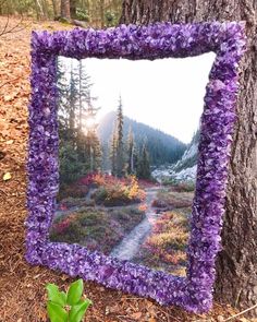 a purple frame sitting on the ground next to a tree with flowers in front of it