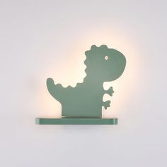 a light that is on the side of a wall with a small dinosaur in it