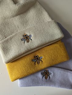 three different colored sweaters with bees on them