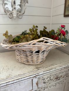 a wicker basket filled with flowers on top of a white dresser next to a mirror