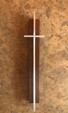 a wooden cross mounted to the side of a wall with a white stripe on it