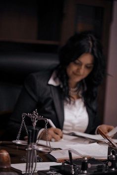 a woman sitting at a desk in front of a scale and papers with a judge's gaven on it