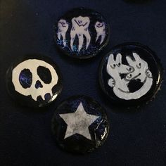 three buttons with different designs on them sitting next to each other in the shape of skulls and stars