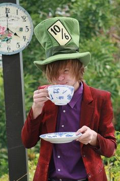 a man in a green hat drinking from a tea cup