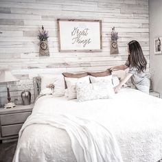 a woman standing on top of a bed next to a wooden headboard and foot board