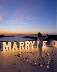 a woman standing on top of a roof next to the word marrye surrounded by candles