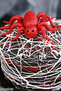 a red spider cake with white icing on it's face and legs, sitting on top of a black plate