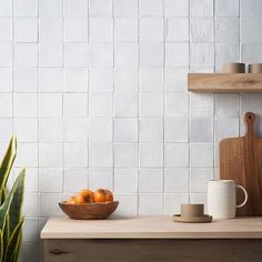 a bowl of oranges sitting on top of a counter next to a cutting board