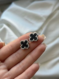 a pair of black and white beaded earrings on someone's hand with their fingers