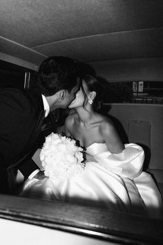 a bride and groom kissing in the back of a car