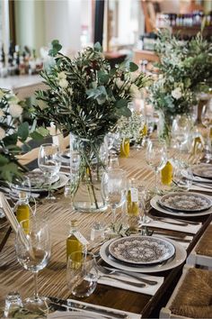 the table is set with place settings and flowers in glass vases on each side